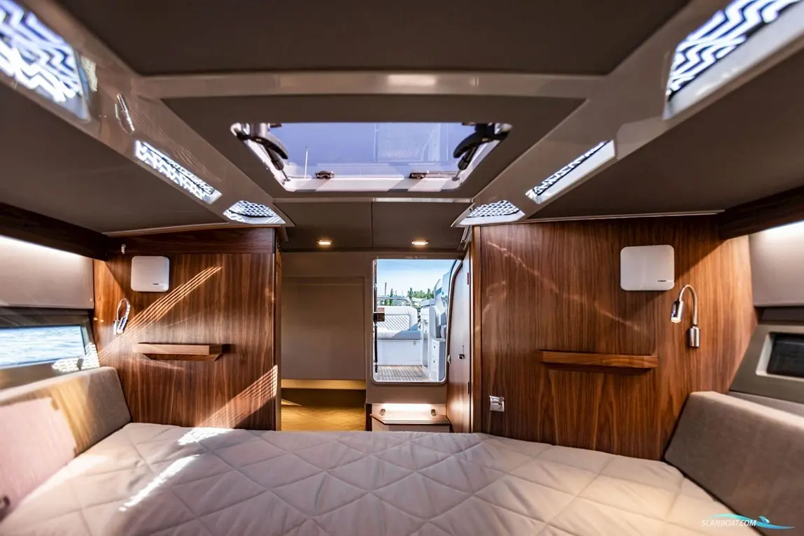 Modern boat interior featuring a double bed, wooden panels, and a skylight, with access to an exterior deck.
